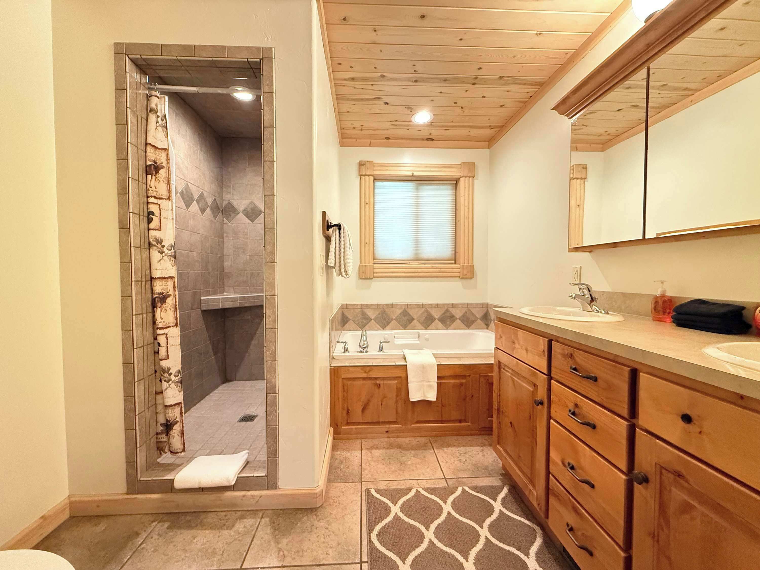 A bathroom with a shower, a sink, and wooden cabinets.