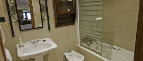 A bathroom with a sink, bidet, and bathtub.