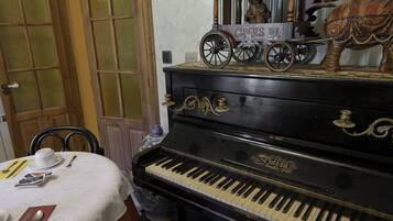 Un piano con motivos circenses en la parte superior, una mesa de comedor con cubiertos, y una puerta con paneles de vidrio esmerilado.