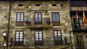 Un edificio de piedra con varias ventanas y balcones, que presenta un estilo arquitectónico tradicional.