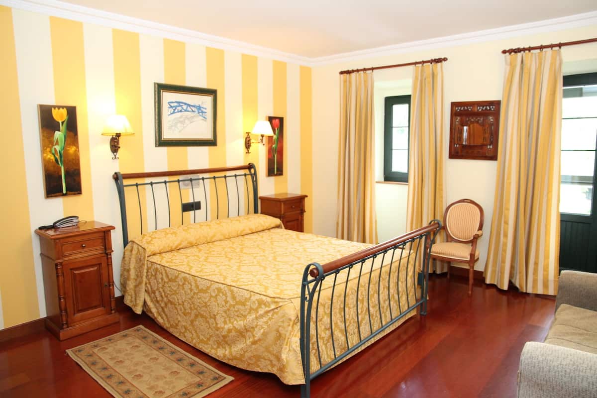 Een slaapkamer met een bed, nachtkastjes, een stoel en gordijnen.