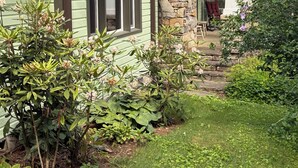 A house with a stone chimney, green siding, and a covered porch. -  Restored Farmhouse 1920s.  Family and Pet Friendly. Borders National forest (Barnardsville)