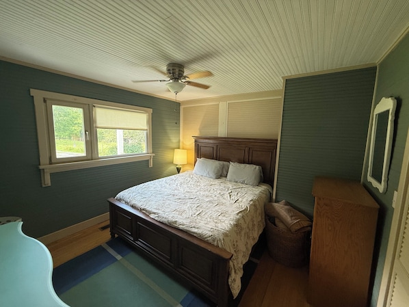 A bedroom with a bed, a ceiling fan, a window, and a nightstand.
