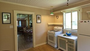 A kitchen with wooden cabinets, a stove, a refrigerator, and a window with a view. -  Restored Farmhouse 1920s.  Family and Pet Friendly. Borders National forest (Barnardsville)