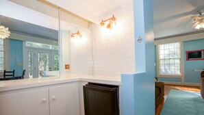 A kitchen with white cabinets, a black dishwasher, and a large mirror above the counter.