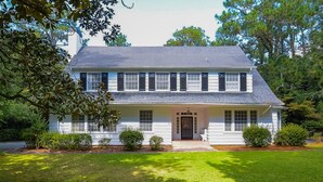 A two-story house with a symmetrical facade, a central entrance, and a well-maintained lawn.