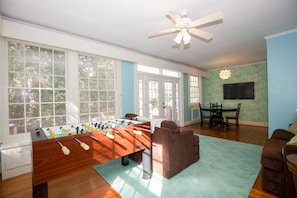 A spacious living room with a foosball table, a brown sofa, and a dining area with a TV. - 65 Blue Road: 6  BR, 6  BA House in Pinehurst, Sleeps 12 (Pinehurst)