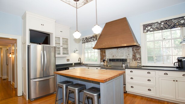 A modern kitchen with a central island, stainless steel appliances, and a large window providing natural light.