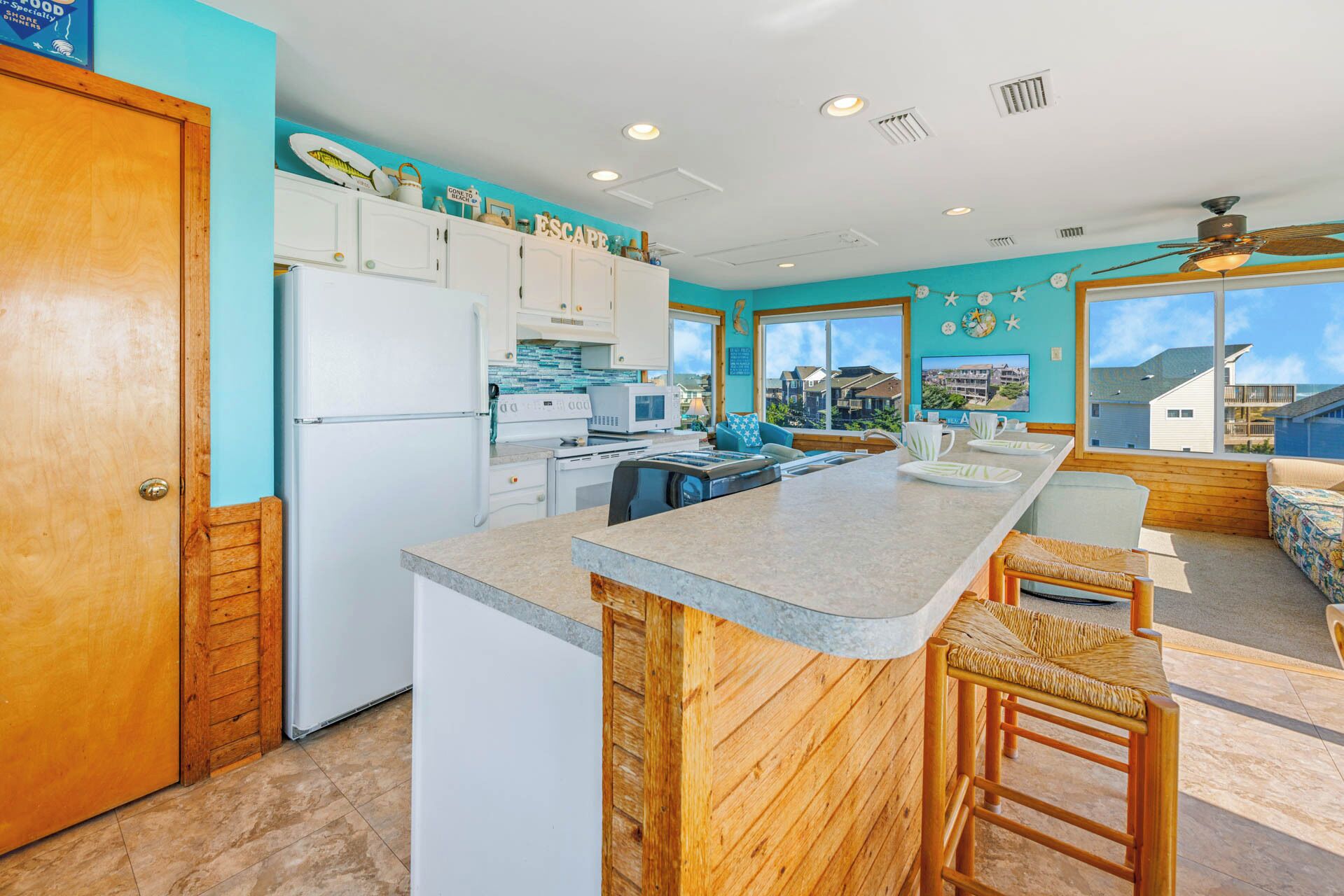 A kitchen with a large island, white cabinets, and a view of the neighborhood.