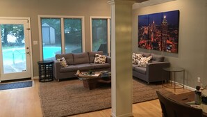 A spacious living room with a gray sofa set, a coffee table, and a cityscape painting on the wall. - Oasis in the City. Morningside/VaHi. Great in town location. (Atlanta)