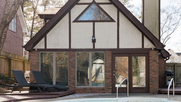 A swimming pool with lounge chairs and a house with a gabled roof and large windows. - Oasis in the City. Morningside/VaHi. Great in town location. (Atlanta)