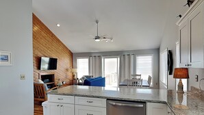 A modern kitchen with white cabinetry, a stainless steel dishwasher, and a granite countertop. - Hicks | Walk to the Beach + Pet Friendly! (Surf City)