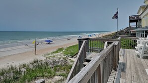 A beach view with a wooden boardwalk, beach umbrellas, and a flag. - Hicks | Walk to the Beach + Pet Friendly! (Surf City)