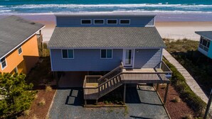 A beachfront house with a covered porch and a staircase leading to the entrance. - Hicks | Walk to the Beach + Pet Friendly! (Surf City)