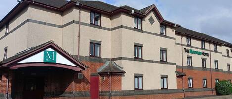A hotel with a brick facade, multiple windows, and a sign for 'The Magnum Hotel'.