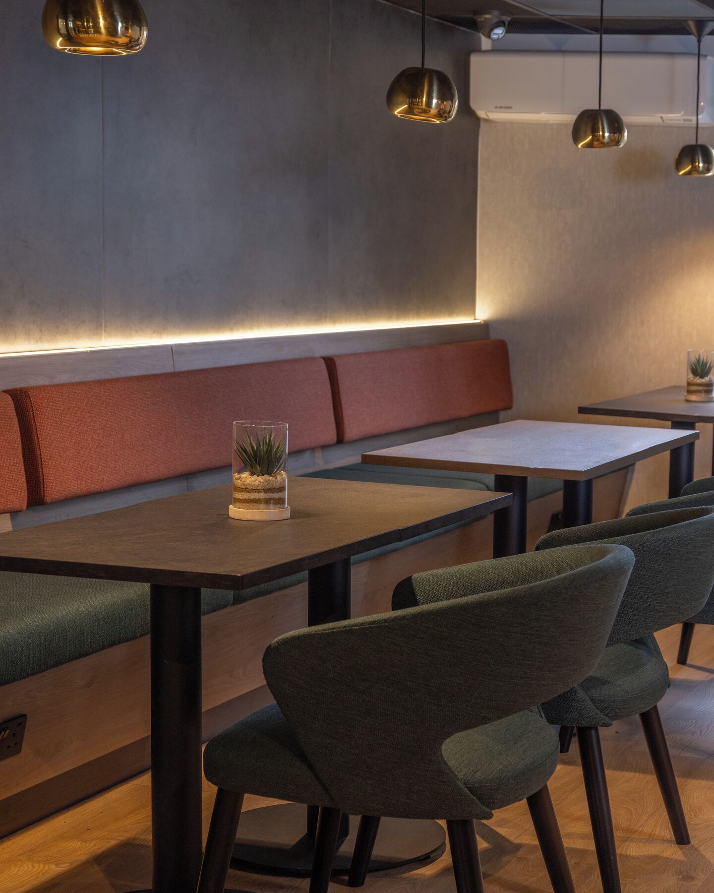 A modern restaurant interior with a long bench, tables, and chairs.