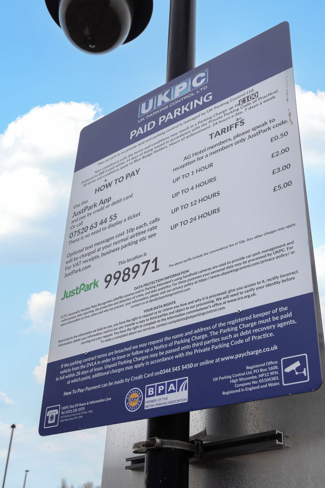 A parking sign with UK Parking Control Ltd. information, including payment methods, tariffs, and contact details.