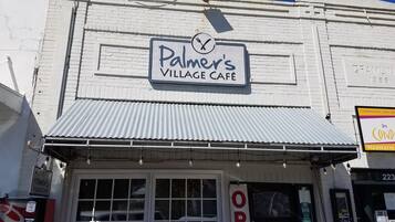 Palmer's Village Cafe mit einem Schild über dem Eingang und einem ‚ÖFFNUNG‘-Schild an der Tür.