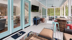 Un espace extérieur abrité doté d’une terrasse en bois, d’une table à manger, de chaises et d’un coin bar.