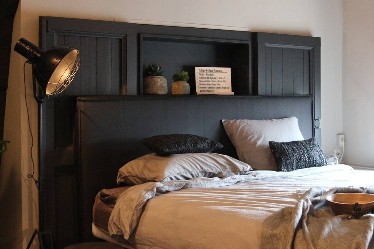 Une chambre à coucher avec un lit, des oreillers, une lampe et un panneau au-dessus du lit.