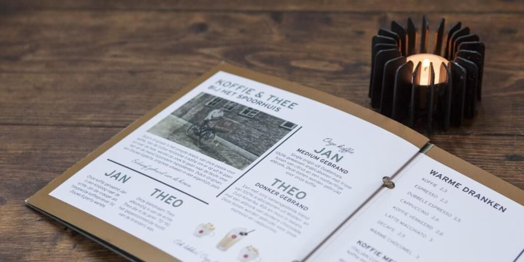 Un menú con opciones de café y té, un candelabro y una mesa de madera.