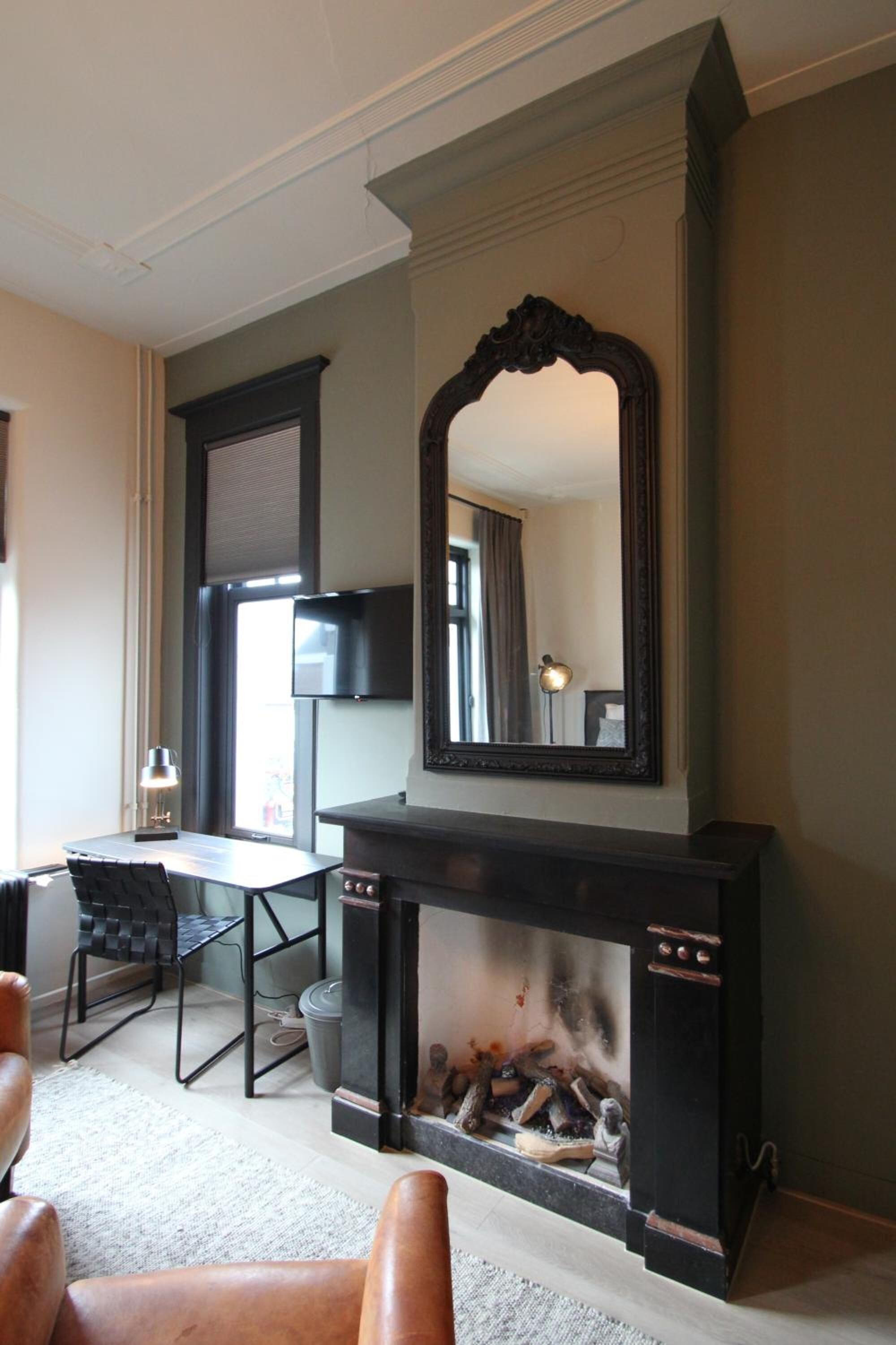 A room with a fireplace, a mirror, a television, and a seating area.