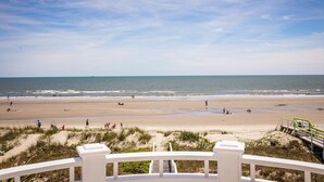 Een strand met een witte balustrade en een trap die naar het zand leidt.