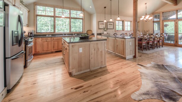 A spacious kitchen with wooden cabinets, a large island, and a dining area with a table and chairs.