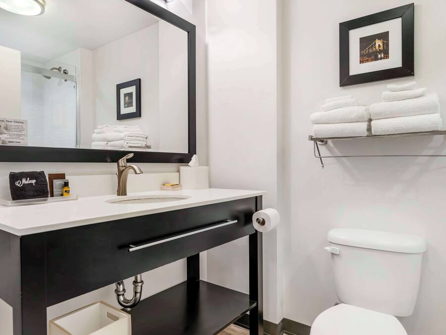 A modern bathroom with a large mirror, a sink, a toilet, and a towel rack.