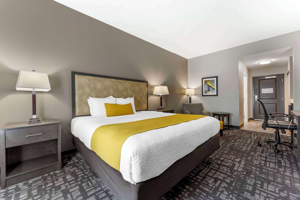 A hotel room with a large bed, two bedside tables with lamps, a desk, and a chair.