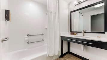 A modern bathroom with a white bathtub, a black vanity, and a large mirror.
