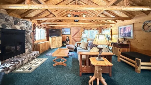 A cozy log cabin interior with a stone fireplace, wooden furniture, and a high wooden ceiling. - 33 MI to YNP | Private Dock | Firepit (Island Park)