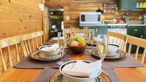 A wooden dining table set for a meal with a bowl of fruit and glasses of white wine. - 33 MI to YNP | Private Dock | Firepit (Island Park)