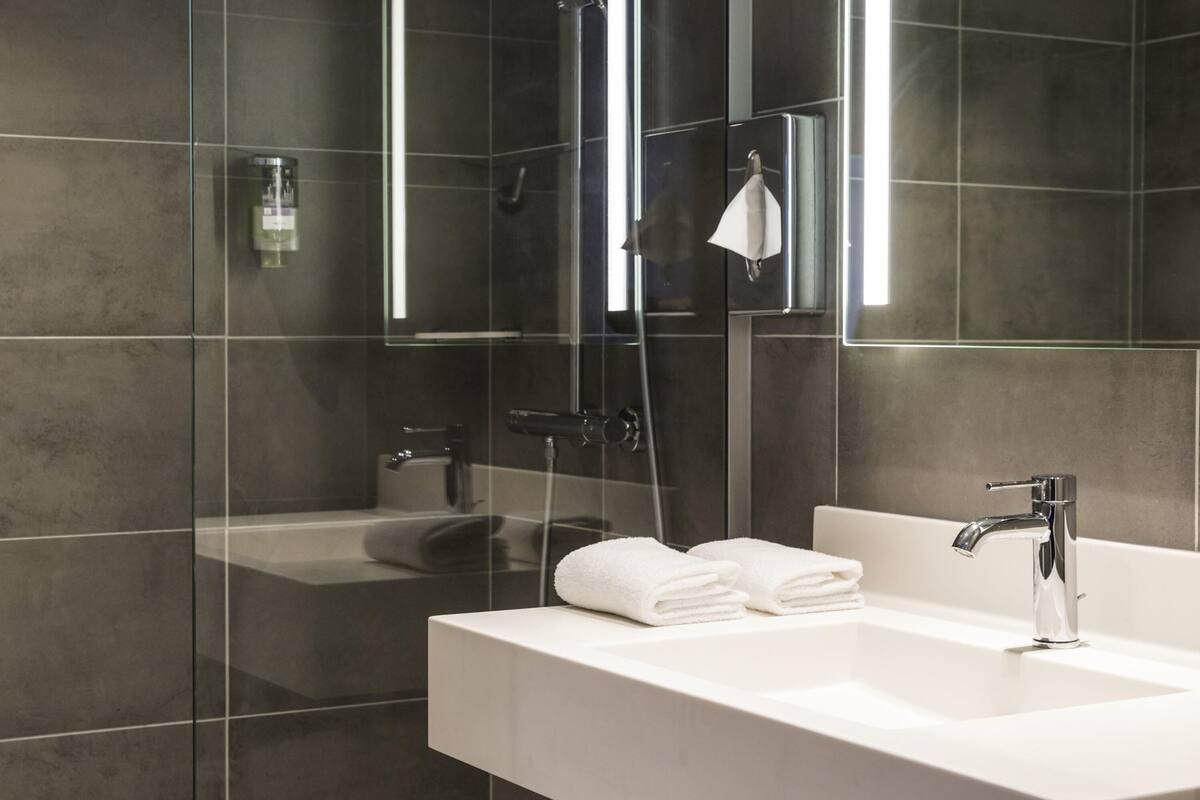 A modern bathroom with a glass-enclosed shower, a white sink, and a mirror.