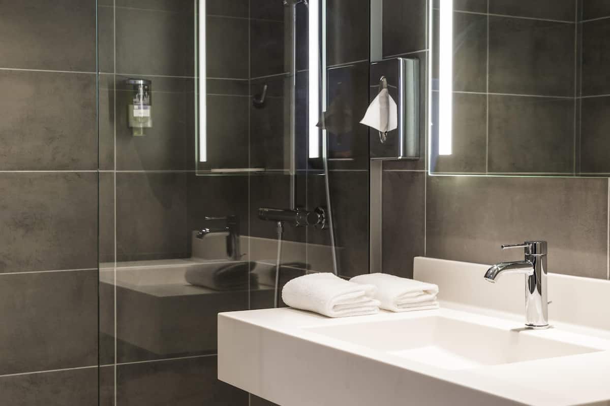 Une salle de bain moderne avec une douche à parois de verre, un lavabo blanc et un miroir.