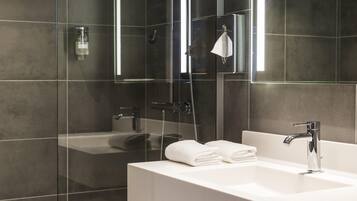 Een moderne badkamer met een douchecabine van glas, een wit wastafelmeubel en een spiegel.