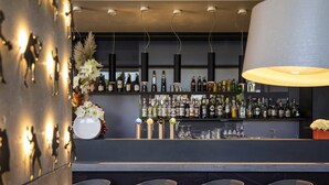 A bar area with a long counter, multiple stools, and a variety of bottles and glasses.