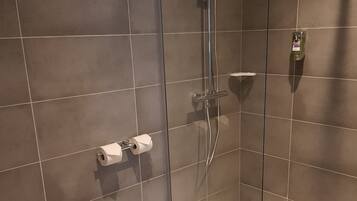 A modern bathroom with a glass-enclosed shower, a toilet, and a sink.
