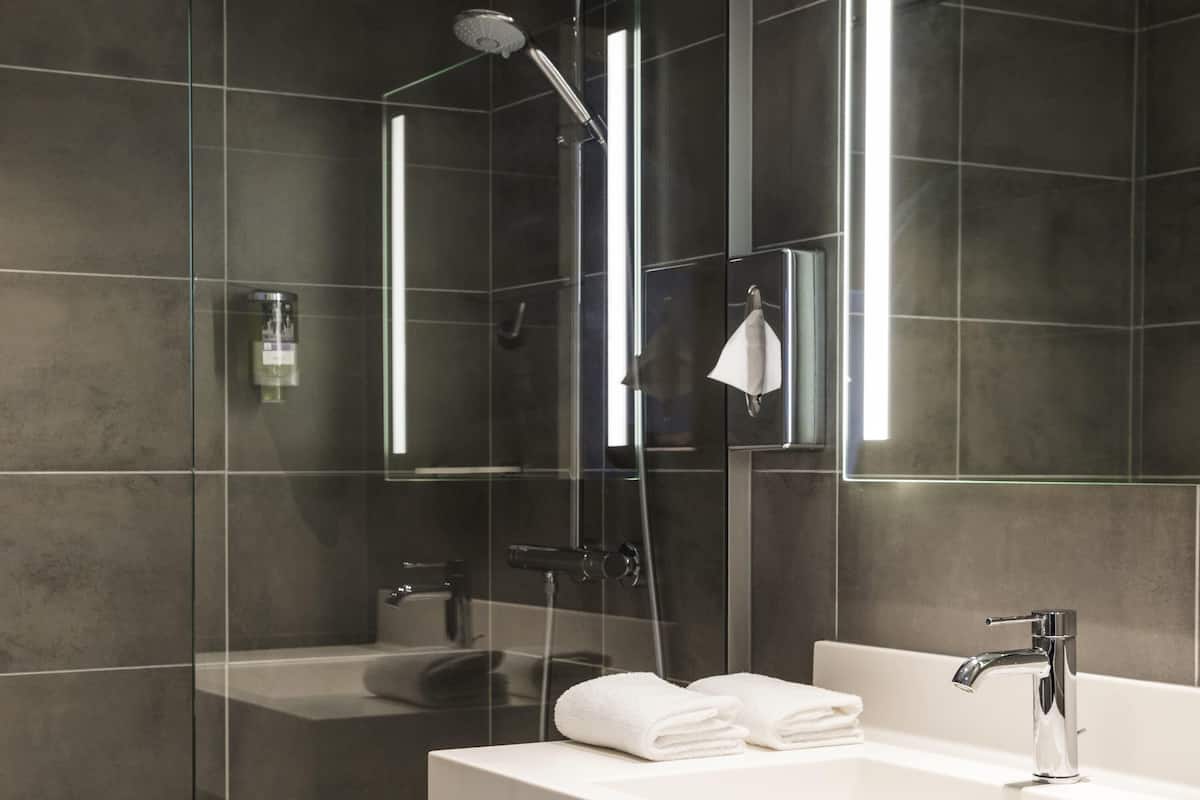 Une salle de bain moderne avec une douche à parois de verre, un lavabo blanc et un grand miroir.