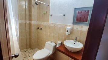 A bathroom with a toilet, sink, shower, and a towel rack.
