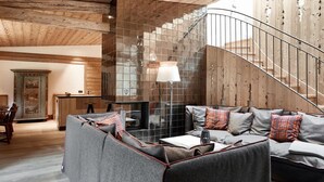 A cozy living room with a fireplace, a sofa, and a staircase. - Kitzbühel Lodge (Reith bei Kitzbuehel)