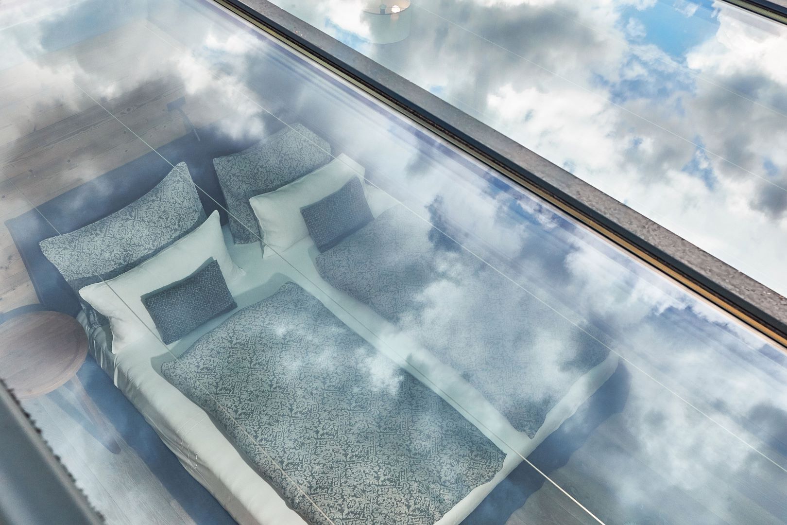 A modern, glass-enclosed seating area with patterned cushions and a clear view of the sky.
