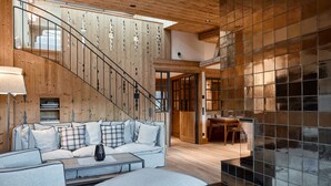 A modern living room with a wooden staircase, a sofa set, and a dining area. - Kitzbühel Lodge (Reith bei Kitzbuehel)