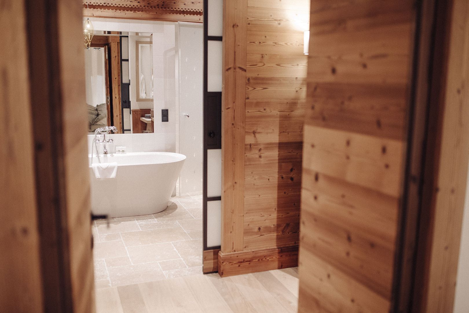 Un corridoio interno in legno che conduce a un bagno con una vasca freestanding.