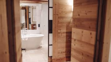 Un corridoio interno in legno che conduce a un bagno con una vasca freestanding.