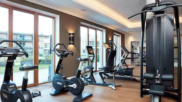 Une salle de sport moderne équipée de divers appareils d’exercice, dotée de grandes fenêtres et offrant une vue sur l’extérieur.