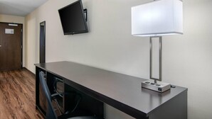 A hotel room with a desk, a flat-screen TV mounted on the wall, and a table lamp. - Econo Lodge Inn & Suites Springfield Main Street (Springfield)