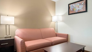 A room with a patterned sofa, a small table, a lamp, and a framed map on the wall. - Econo Lodge Inn & Suites Springfield Main Street (Springfield)