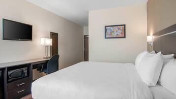 Ein Hotelzimmer mit Bett, Schreibtisch, Flachbildfernseher, Mikrowelle und Stuhl.