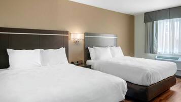 A hotel room with two beds, a nightstand with a lamp, and a large window with curtains.